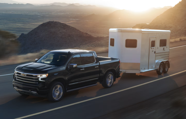 chevrolet truck pulling trailer on highway with mountains in back